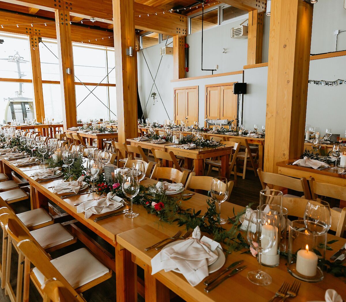 Long banquet tables set with glassware and greenery inside Summit Lodge